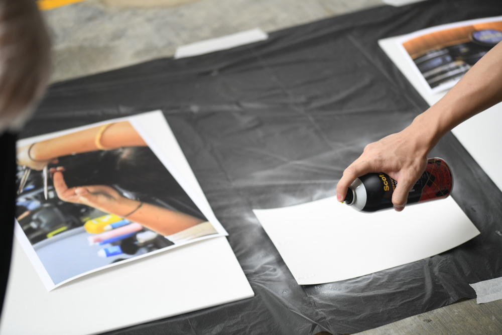 First, they sprayed adhesive all over their photography prints. (Photo by Alden Boon)