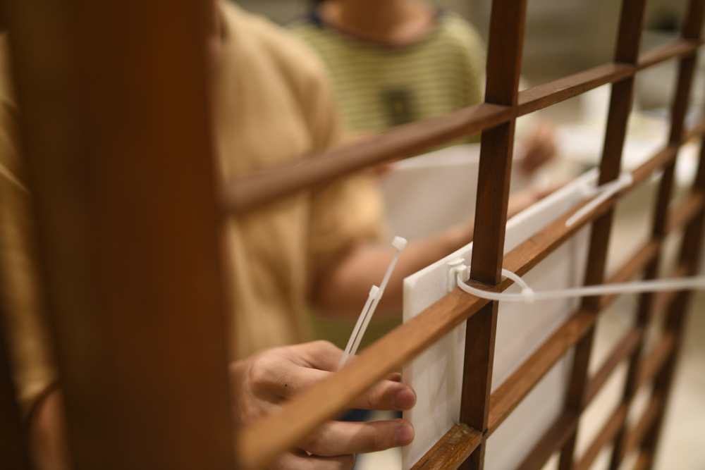 Using cable ties, they mounted their prints to the exhibition panels. (Photo by Alden Boon)