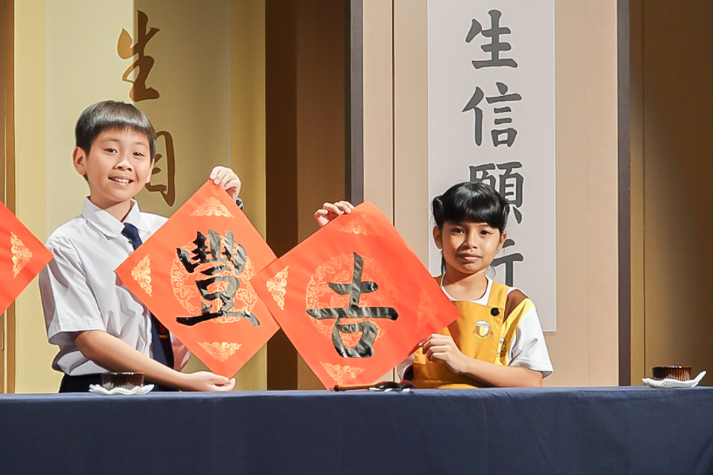 Young calligraphy students showcasing their skills on stage, earning applause for their impressive writing. (Photo by Lee Foo Tien)